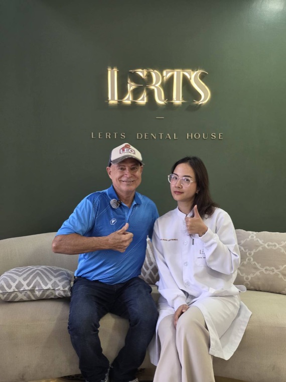 Patient and clinician giving a thumbs up at the Dental Excellence logo wall, Chiang Mai